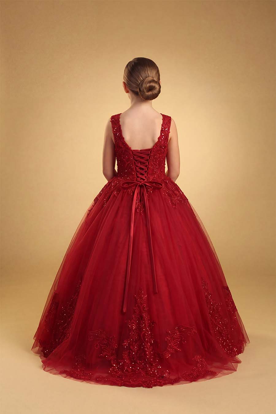 a girl wearing a deep burgundy color ball-gown in a gold background